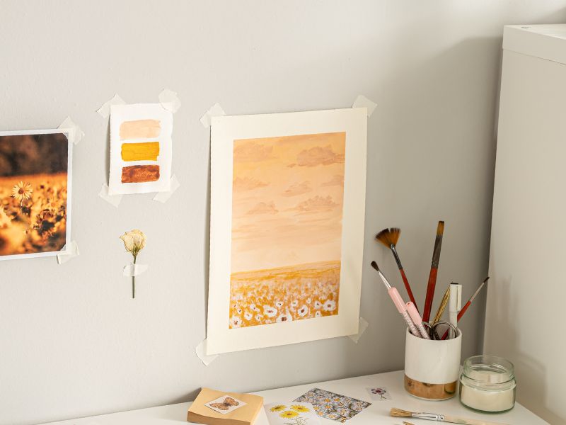 Affordable DIY projects: a cozy workspace featuring handmade wall art, paintbrushes, and creative materials for home decor