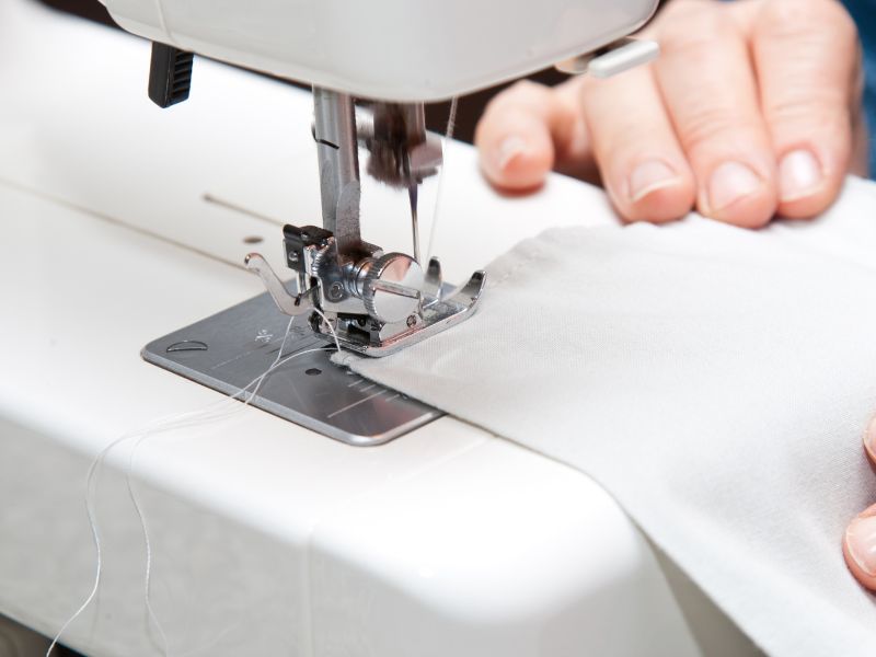 Affordable DIY projects: hands sewing fabric on a machine, creating custom curtains or drapes for personalized home decor