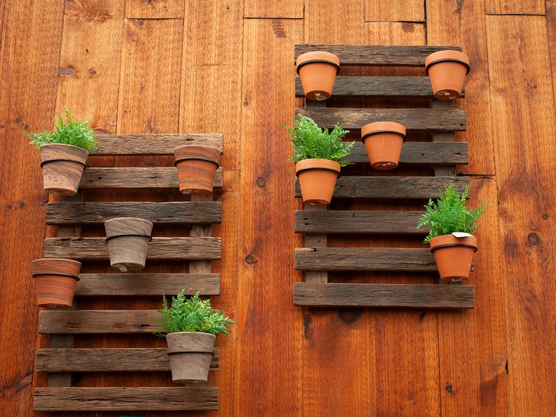 DIY garden projects: rustic wooden pallets repurposed as vertical planters with terracotta pots for herbs and greenery