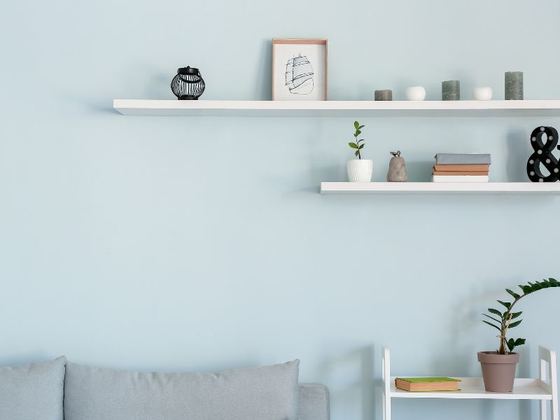 Affordable DIY projects: minimalist white floating shelves on a pastel wall, styled with decor and small plants for a modern look