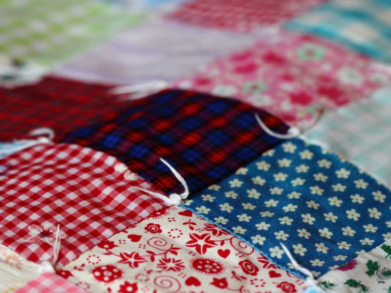 DIY blanket projects: a vibrant tied quilt made from colorful fabric squares with floral, plaid, and gingham patterns