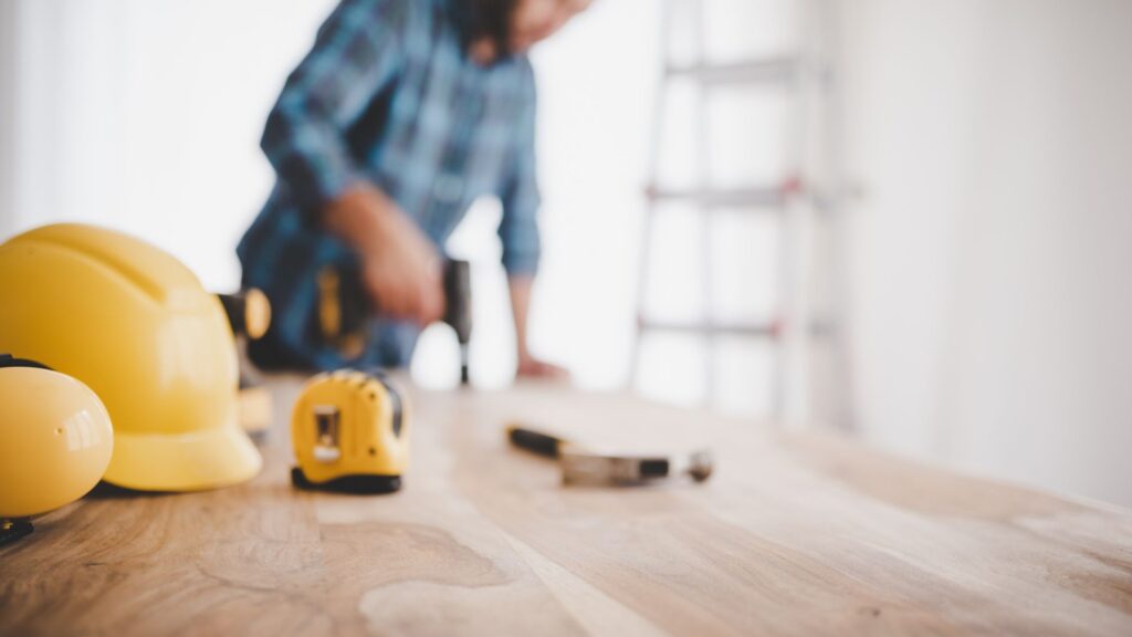 Affordable DIY projects: a workspace with tools, a hard hat, and a person preparing for a budget-friendly home improvement task