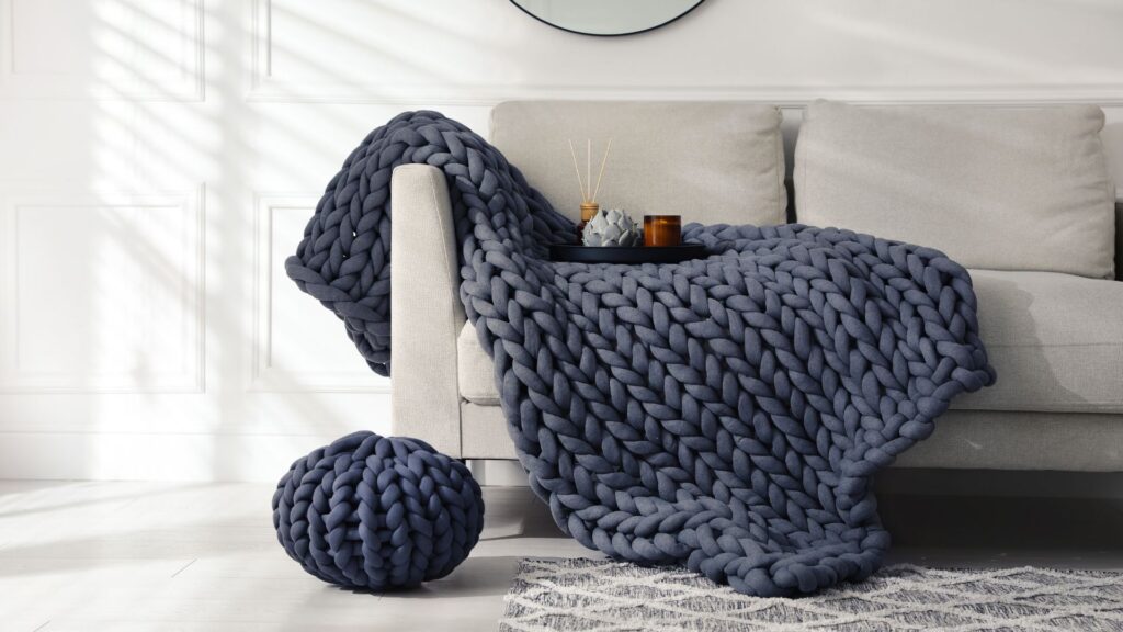 DIY blanket projects: Chunky knit blanket draped over a couch in a cozy living room