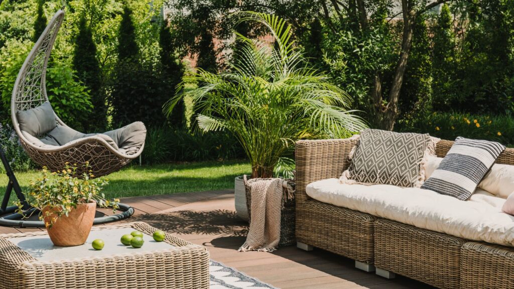 DIY garden projects: outdoor patio with wicker furniture, a hanging chair, and lush greenery